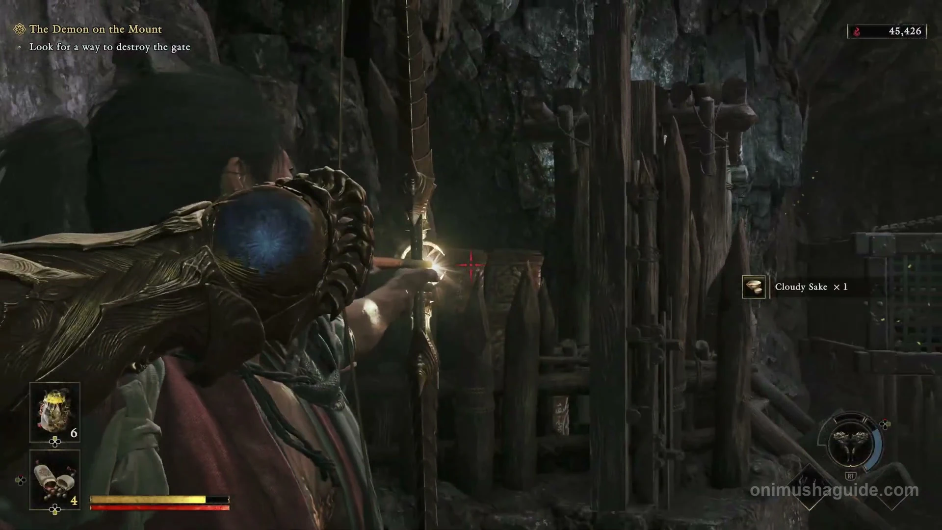 Bow aimed through the timber gate at the explosive barrel behind it