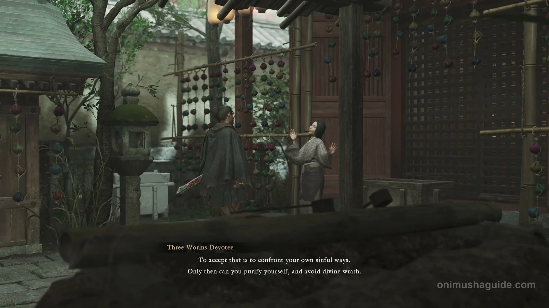 Three Worms Devotee standing at the small shrine with strings of colored cloth balls